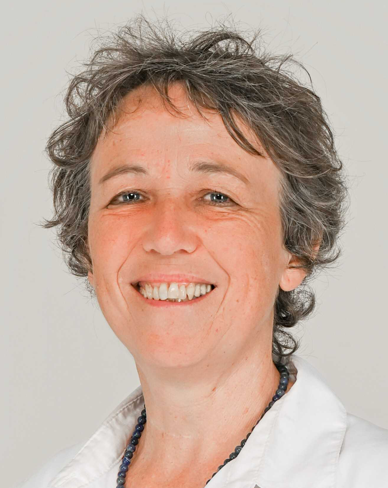 Portrait de Anne DELMAS souriante et qui porte une chemise blanche